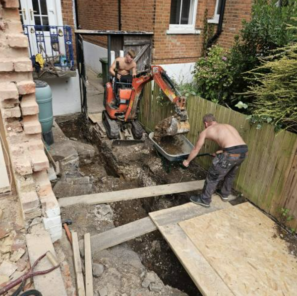 Digger and barrow team digging out a rear garden foundation