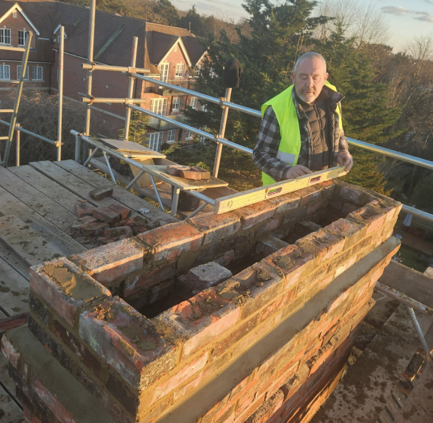 Rebuilding a chimney stack brick by brick on the scaffold