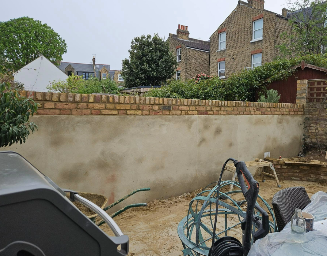 Rebuilt garden wall with new brick copings and render