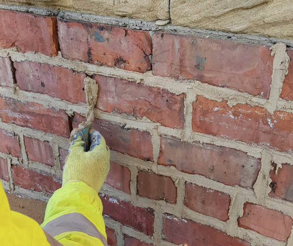 Pressing lime mortar into weathered joints by hand