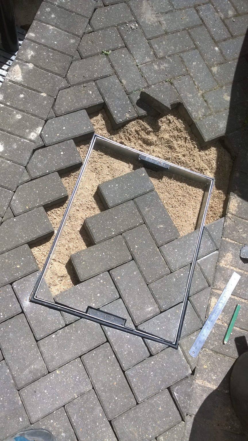 Inspection chamber frames cut into a block-paved driveway