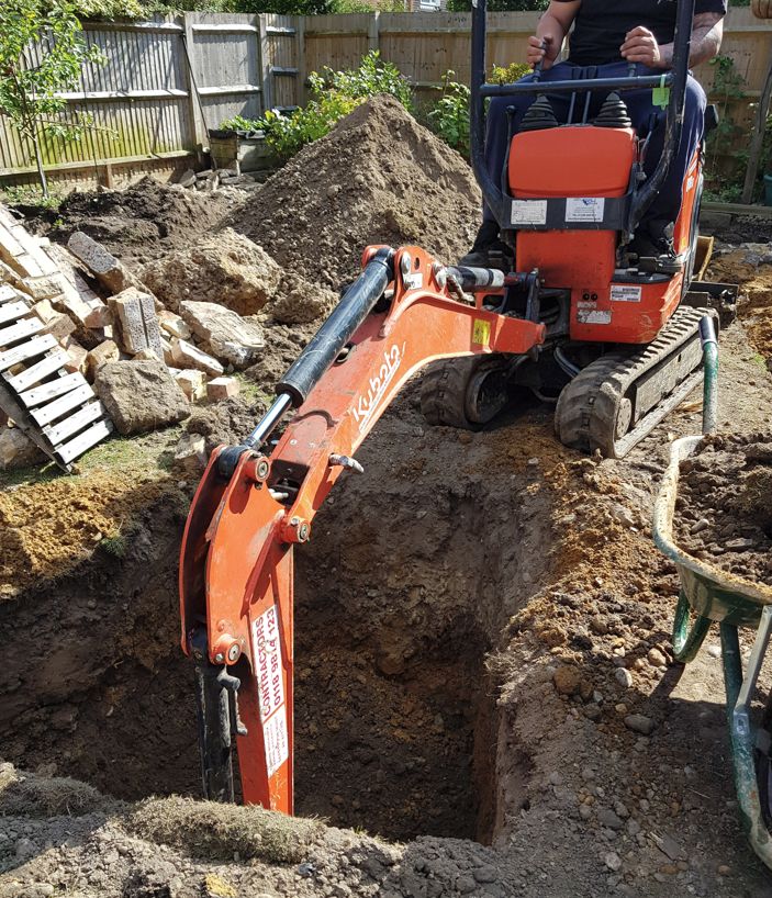 Mini digger digging out a new soakaway pit