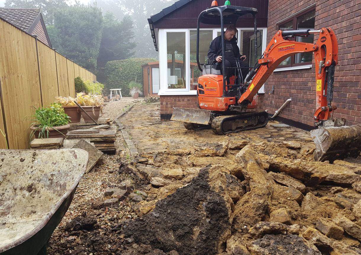 Mini digger breaking out an old patio ahead of a new build-over