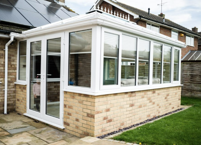 White conservatory on a buff-brick base with dwarf wall