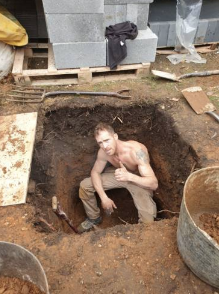 Ricky hand-digging a drain inspection pit