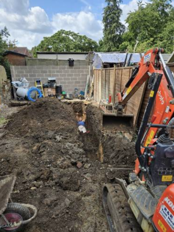 Mini digger excavating a deep trench for new footings