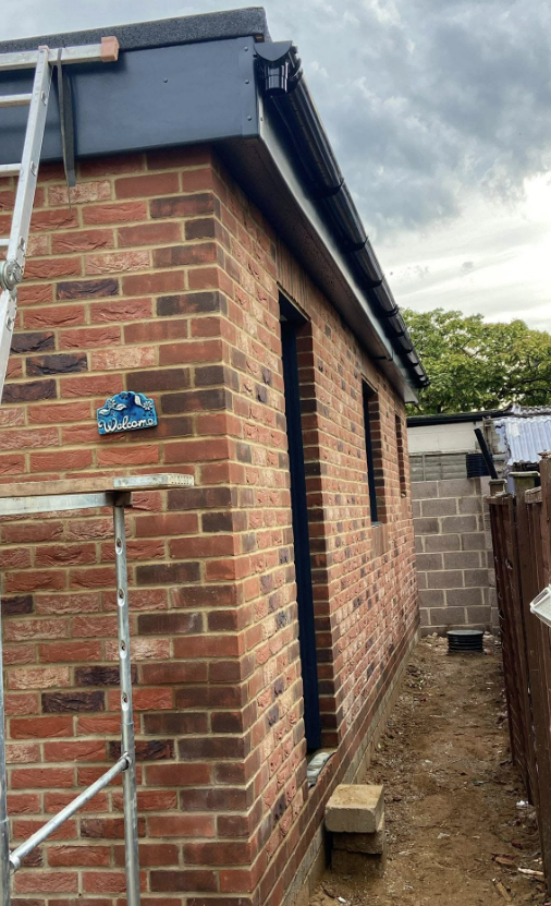 New red-brick garage extension with flat roof and guttering