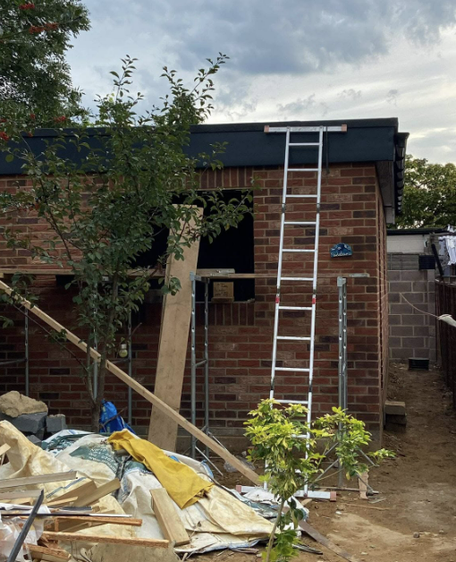 Red-brick garage build taking shape with ladder access