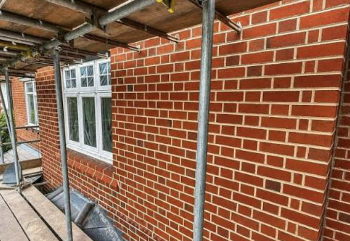 Re-pointed red-brick elevation under scaffold with period window detail
