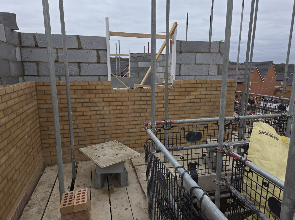 Brick and block walls on the flat roofline under scaffold