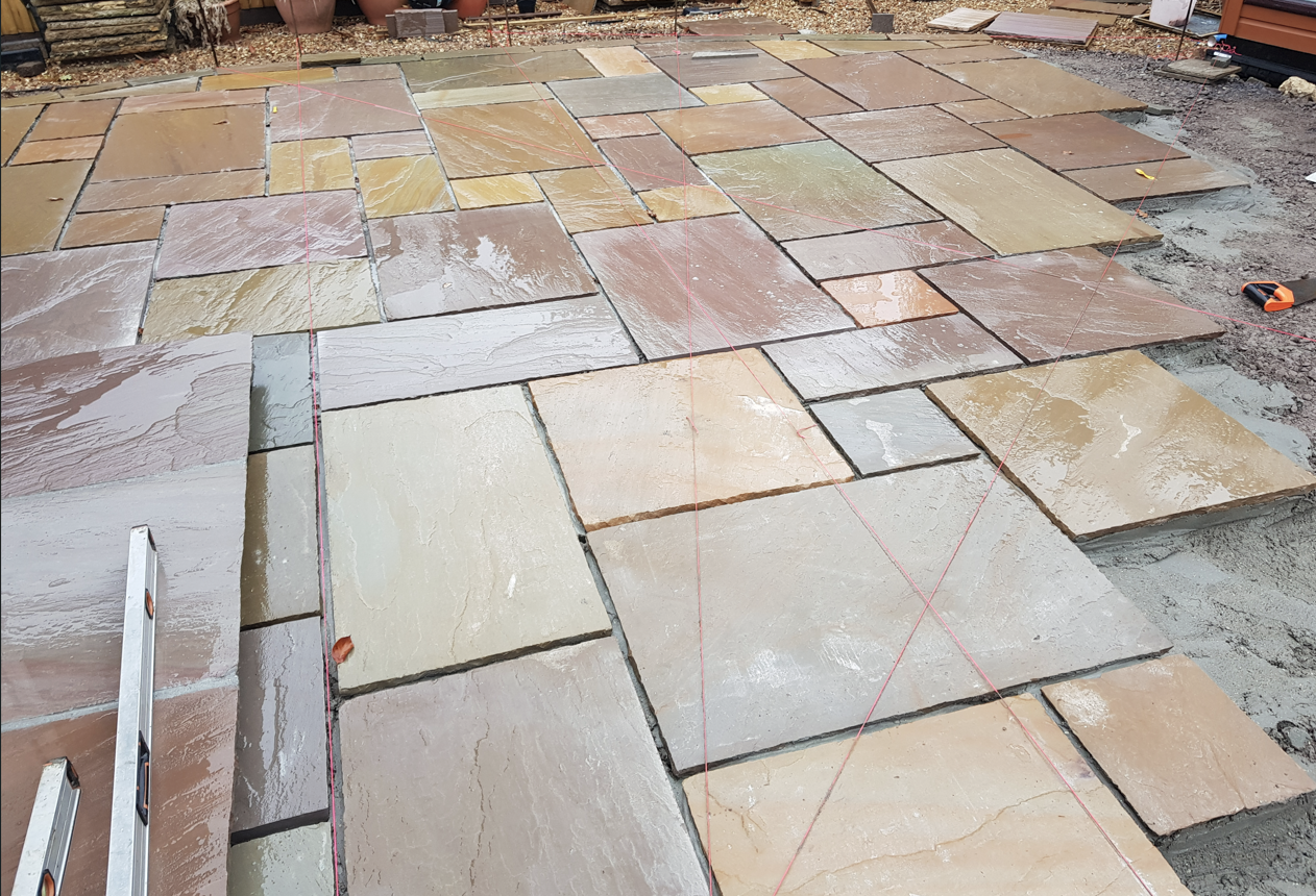 Sandstone patio slabs laid to string lines on a full bed