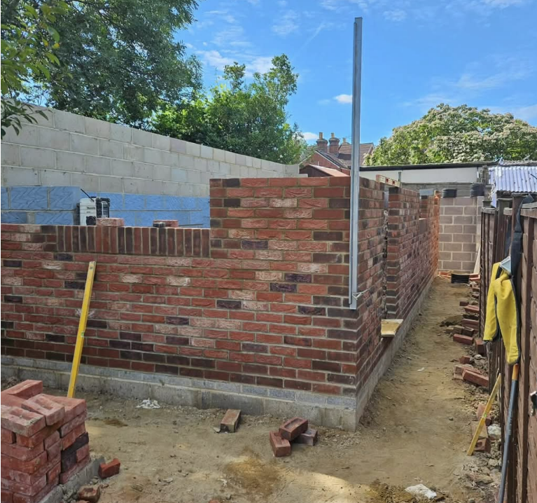 Red-brick extension walls under construction with steel support