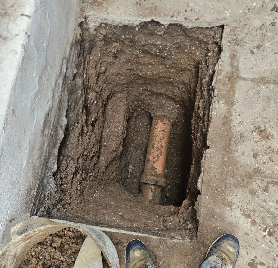 Excavation exposing an existing clay drain pipe