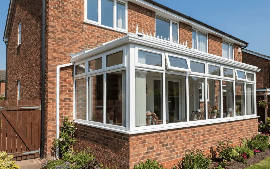 White conservatory with full-height glazing on a red-brick base