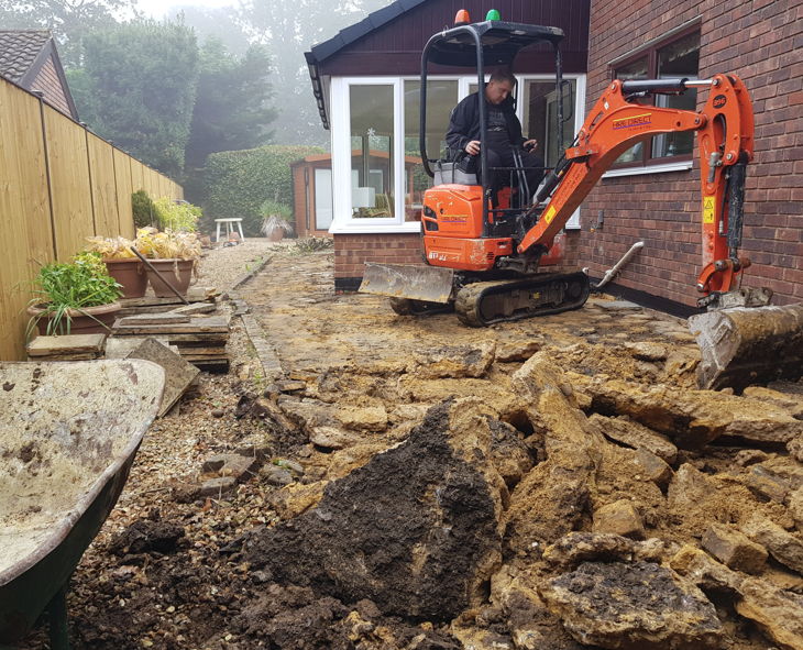 Removing an old patio slab by slab with a mini digger