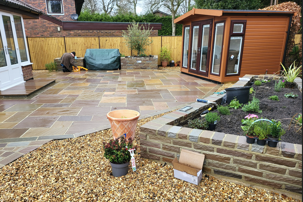 Stone and brick raised beds planted up next to a summerhouse